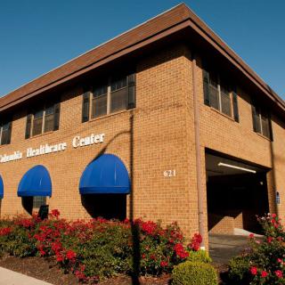 A brick commercial building with blue awnings and landscaped surroundings on a sunny day.