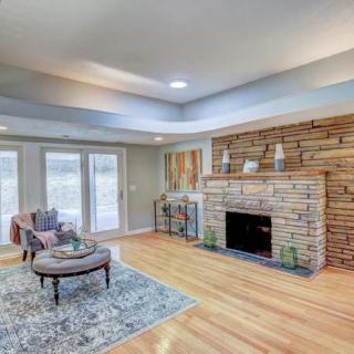 A cozy living room with a stone fireplace, wooden flooring, and a comfortable seating area.