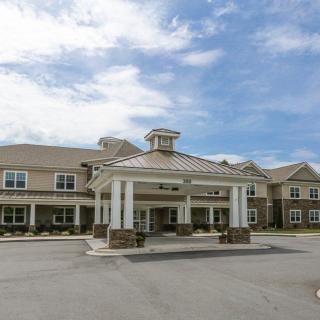A large building with a prominent entrance and a cloudy sky in the background.
