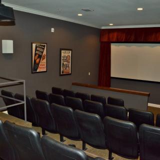 A cozy home theater with tiered seating and a large screen.