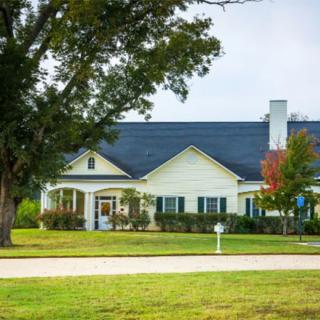 A suburban house surrounded by trees and a well-maintained lawn.