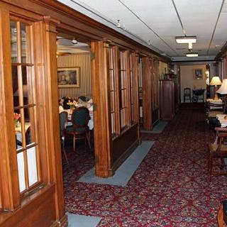 A cozy interior hallway leading to a dining area, featuring wood paneling and a patterned carpet.