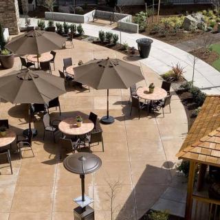 An outdoor patio area with tables, chairs, and umbrellas arranged in a courtyard.