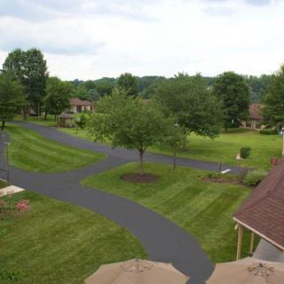 A scenic view of a suburban residential area with a neatly paved driveway and well-maintained lawns.