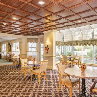 An elegant dining area with wooden chairs, round tables, and a patterned carpet.