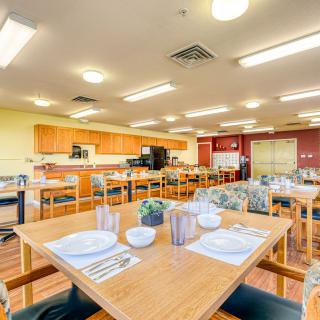 A brightly lit dining area with neatly arranged tables and chairs, ready for guests.