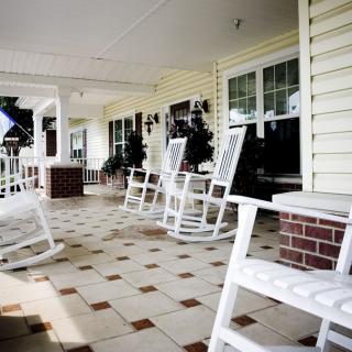 A cozy porch with white rocking chairs and a tiled floor.