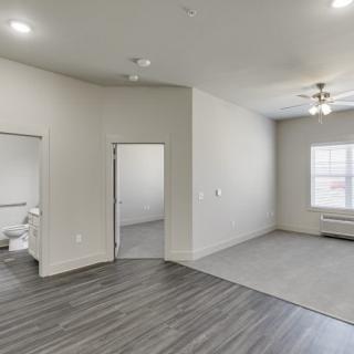 A modern apartment interior with gray flooring, white walls, and ample natural light.