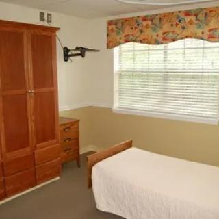 A cozy bedroom with a single bed, wardrobe, and a window adorned with floral curtains.