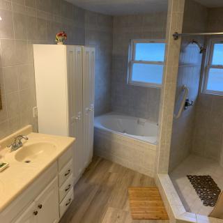 A modern bathroom featuring a bathtub, shower, and sink with a cabinet and mirror.