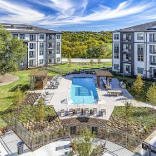 A beautifully designed residential complex featuring a serene swimming pool surrounded by landscaped gardens, ideal for relaxation and leisure.