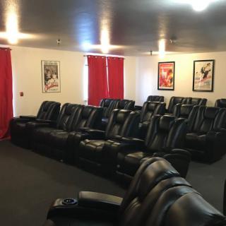 A cozy home theater setup with rows of leather recliners and movie posters adorning the walls.