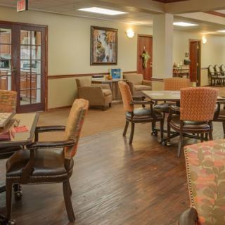 A cozy dining area with wooden floors, surrounded by comfortable chairs and tables.