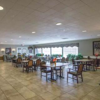 A spacious dining area with multiple tables and chairs, well-lit by natural light from large windows.