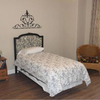 A cozy bedroom with a single decorated bed, featuring patterned bedding and a decorative headboard.