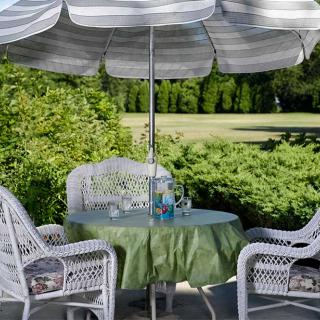 A cozy outdoor patio setup with a table, chairs, and an umbrella amidst lush greenery.