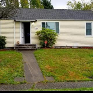 A small single-story house with a front lawn and pathway leading to the entrance on an overcast day.