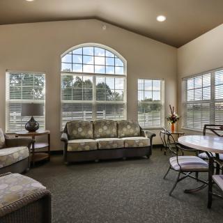 A bright and spacious living room with large windows, comfortable sofas, and a dining table with chairs.