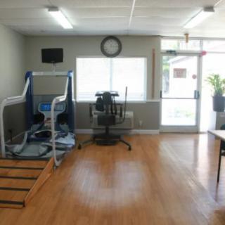 A small fitness room with exercise equipment, including a treadmill, on a wooden floor.