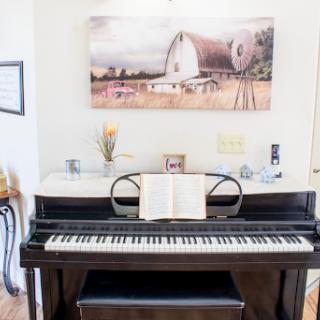 A beautifully arranged piano scene featuring a sheet of music and artwork in the background.