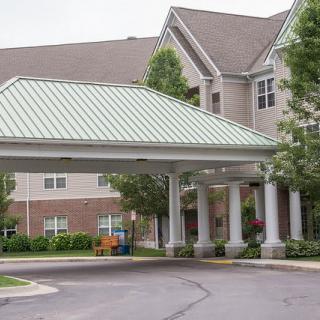A building entrance with a covered canopy and columns surrounded by trees.