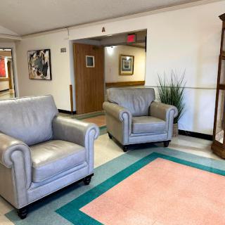 A cozy lounge area featuring two gray leather chairs, decorative plants, and artwork on the walls.