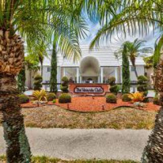 Entrance to a building framed by palm trees and landscaped gardens.