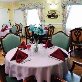 A well-decorated dining room with tables set for a meal, featuring elegant tableware and floral centerpieces.