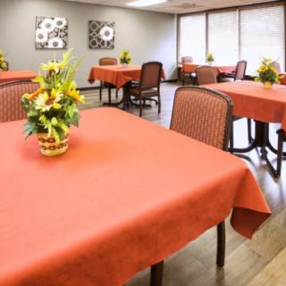 A dining room with tables covered in red tablecloths, decorated with flower arrangements.