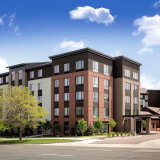 A modern hotel building with a mix of brick and white facade under a clear blue sky.