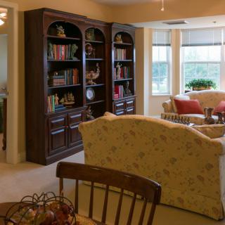 A cozy living room with large bookshelves, a comfortable sofa, and plenty of natural light.