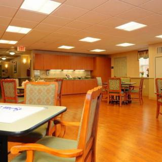 An empty dining area with wooden floors, tables, and chairs under bright lighting.