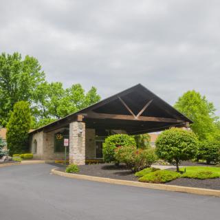 A landscaped building entrance with a driveway on an overcast day.