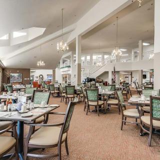 A spacious dining area with neatly arranged tables and chairs, lit by chandeliers.