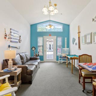A cozy living space with a blue accent wall, featuring a sofa and chairs arranged around a coffee table under soft indoor lighting.