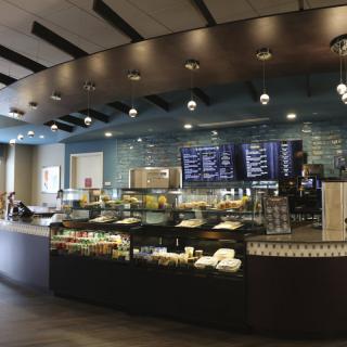 Modern cafe interior with a display counter and menu boards.