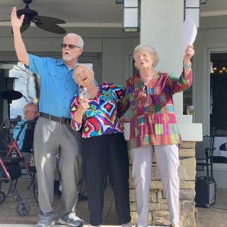 A joyful group of seniors celebrating outdoors with a microphone.