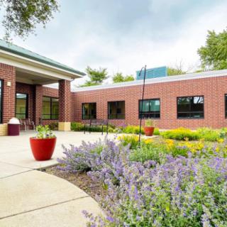 Exterior view of a brick school building with landscaped greenery and a walkway.