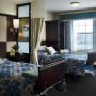 A hospital room with two beds and medical equipment by the window.