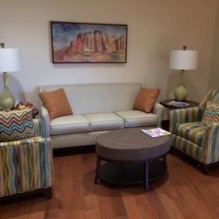 A cozy living room with a sofa, two armchairs, a coffee table, and decorative lamps.