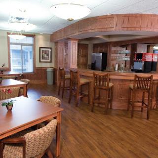A cozy common area featuring wooden furniture and a kitchenette, perfect for social gatherings.