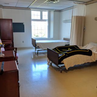 A spacious patient room in a hospital, featuring two beds and essential furniture.