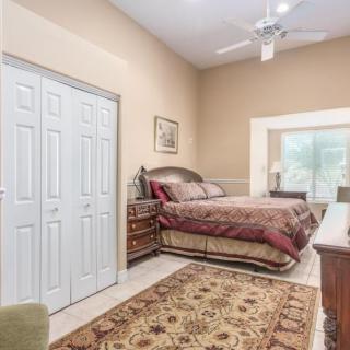 A cozy bedroom with a large bed, closet, ceiling fan, and decorative rug.
