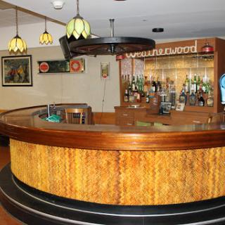 A cozy bar interior featuring a wooden counter and ambient lighting.