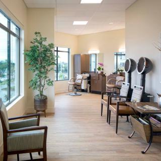 A spacious and well-lit salon with multiple hair styling stations, mirrors, and comfortable seating.