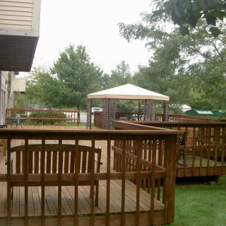 A backyard deck featuring wooden furniture and a gazebo.