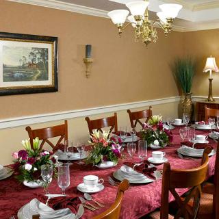 A beautifully set formal dining table with elegant place settings and floral centerpieces under a chandelier.