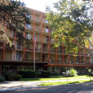 A residential apartment building with balconies and surrounding trees.