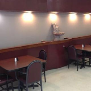 An empty restaurant interior with tables and chairs arranged under soft lighting.