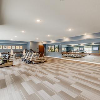 A spacious gym with modern exercise equipment and large mirrors.